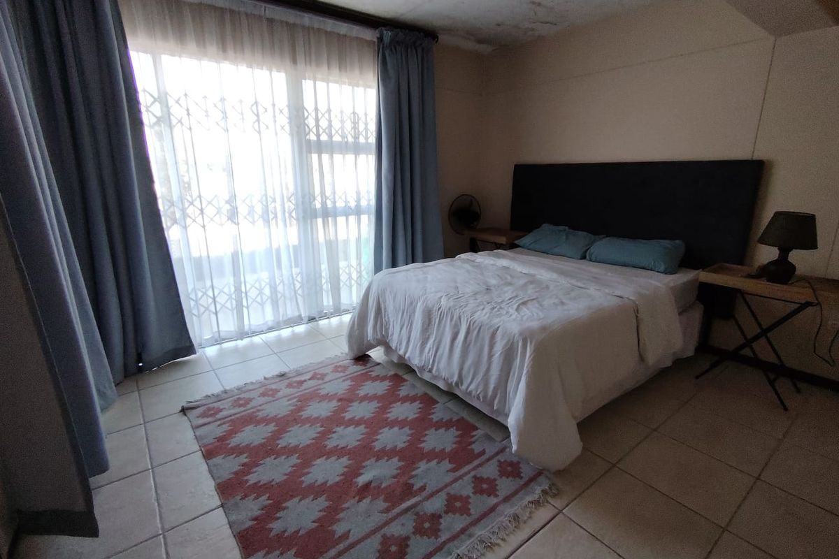 A bedroom featuring tiled flooring, a large sliding door with security gate, and visible water damage on the ceiling.