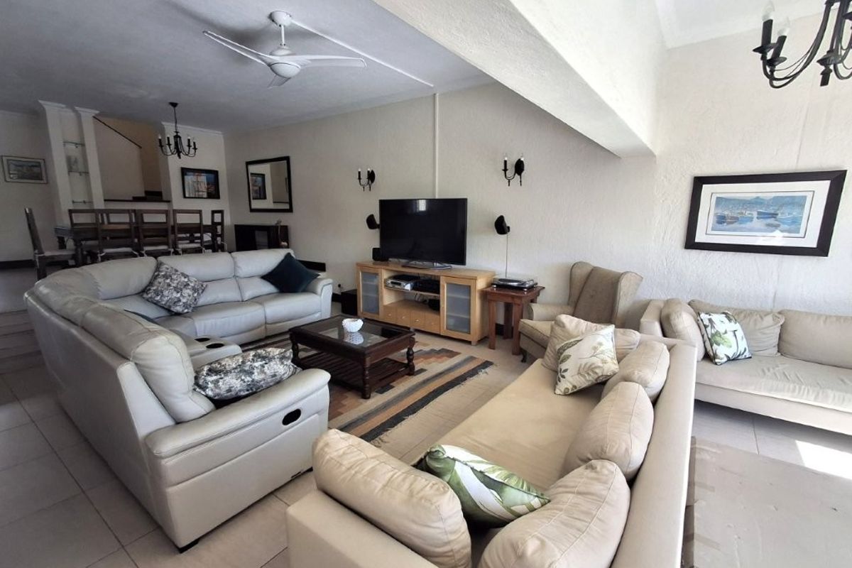Spacious open-plan living area featuring tiled flooring, ceiling fan, and wall-mounted lighting fixtures, providing a comfortable and functional space for relaxation.