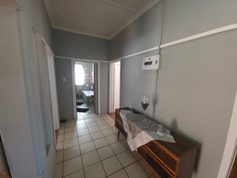 A functional hallway featuring ceramic floor tiles, coving, and a wall-mounted electrical distribution board with visible conduit.