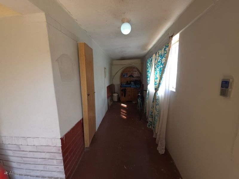 A narrow hallway featuring a security alarm keypad, ceiling lighting, and built-in storage, requiring cosmetic updates to improve the overall condition.