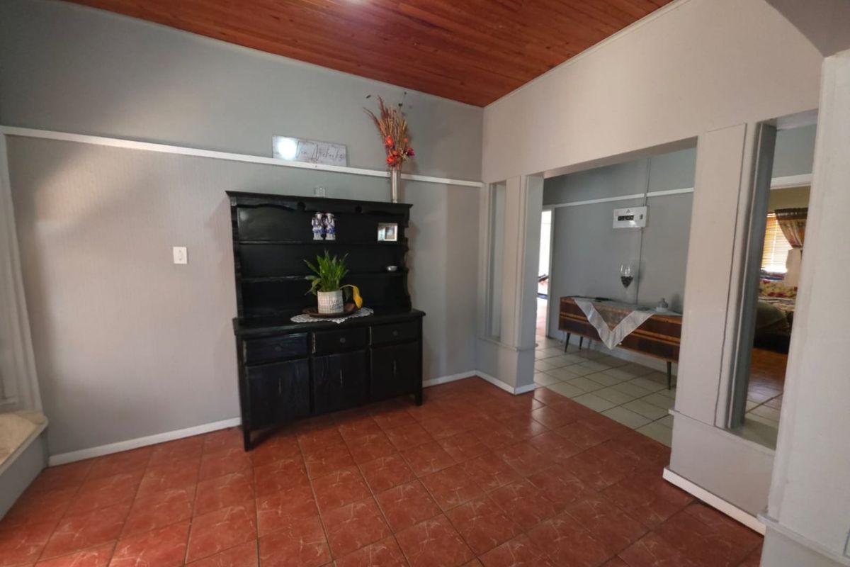 A living area featuring warm timber tongue and groove ceilings, ceramic floor tiles, and a classic archway leading to an adjacent space.