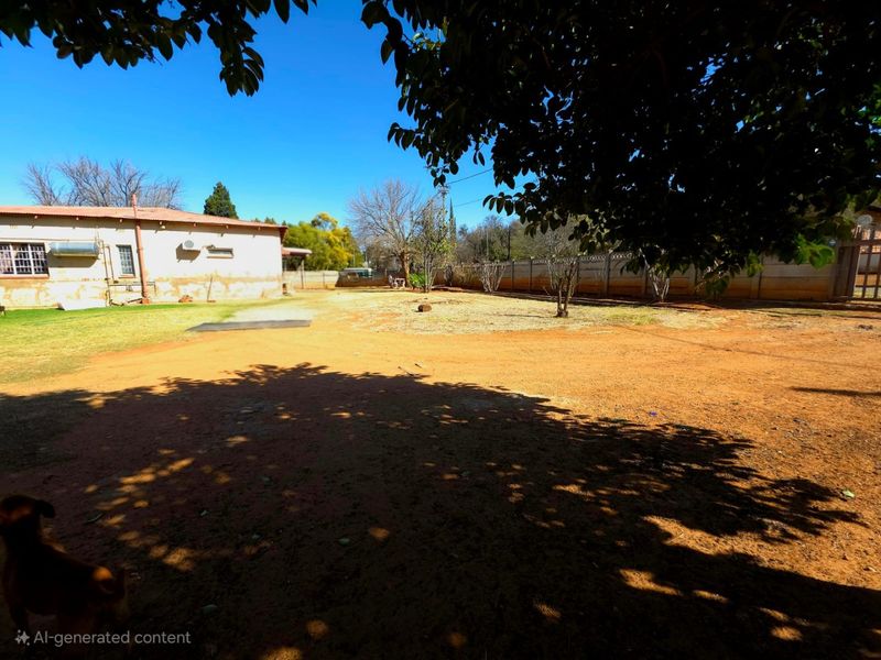 Spacious rear garden area featuring a perimeter wall, solar geyser, and external air conditioning unit, with significant potential for landscaping improvements.