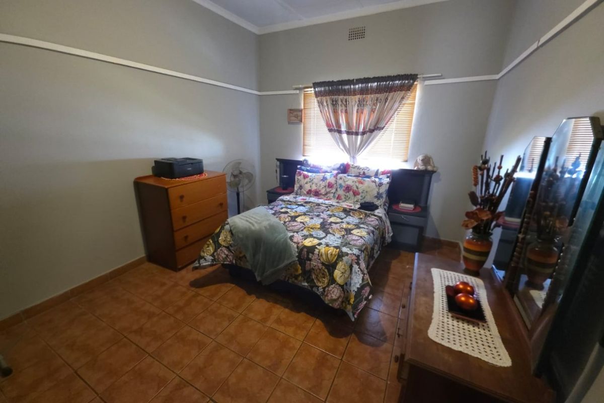 A bedroom featuring tiled flooring, a picture rail, and a ceiling vent, providing a functional and well-lit sleeping space.