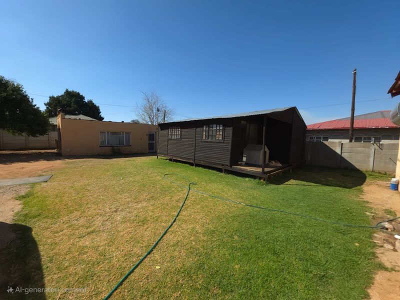 Rear garden area featuring a detached timber cabin structure, lawn, and perimeter boundary walling.