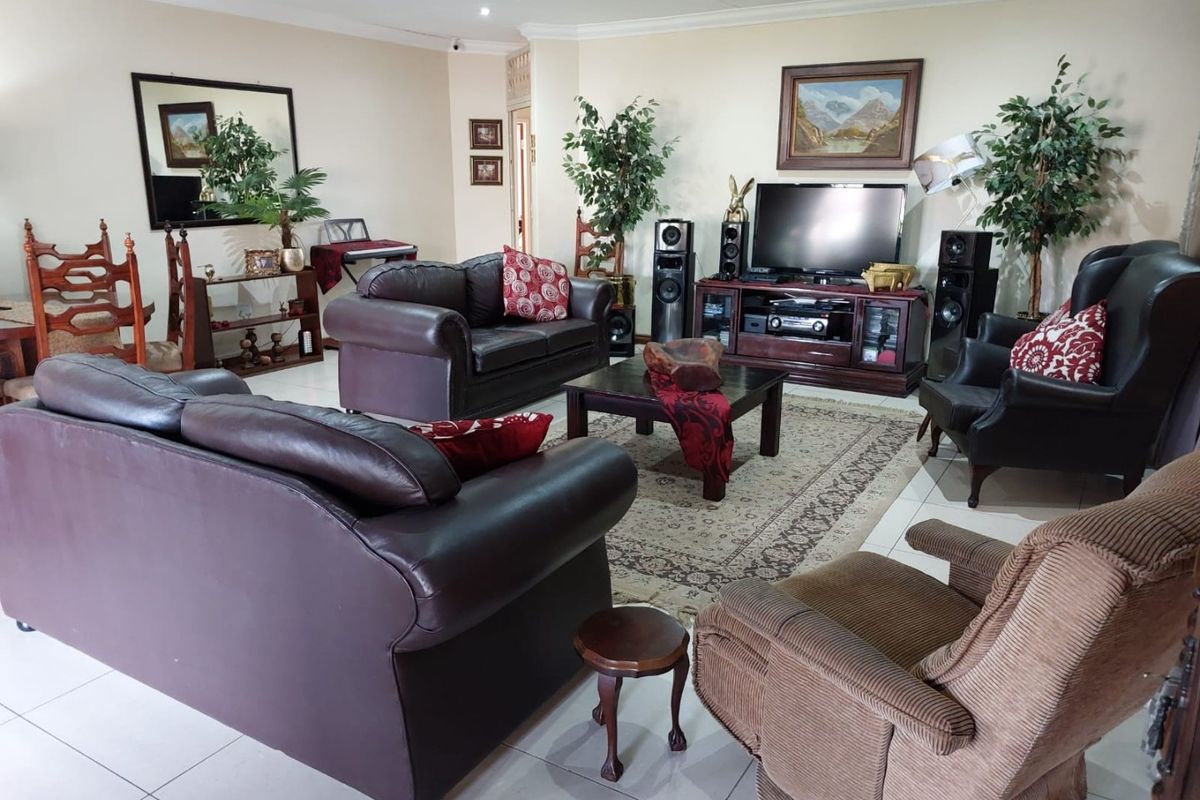 A spacious living room featuring neutral wall tones, tiled flooring, and recessed downlighting, offering a comfortable and functional layout for relaxation.