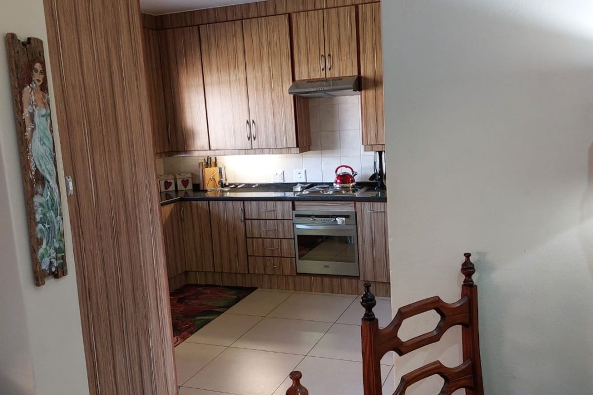 A functional kitchen featuring wood-look laminate cabinetry, built-in oven, extractor fan, and tiled flooring, offering a practical layout for daily meal preparation.
