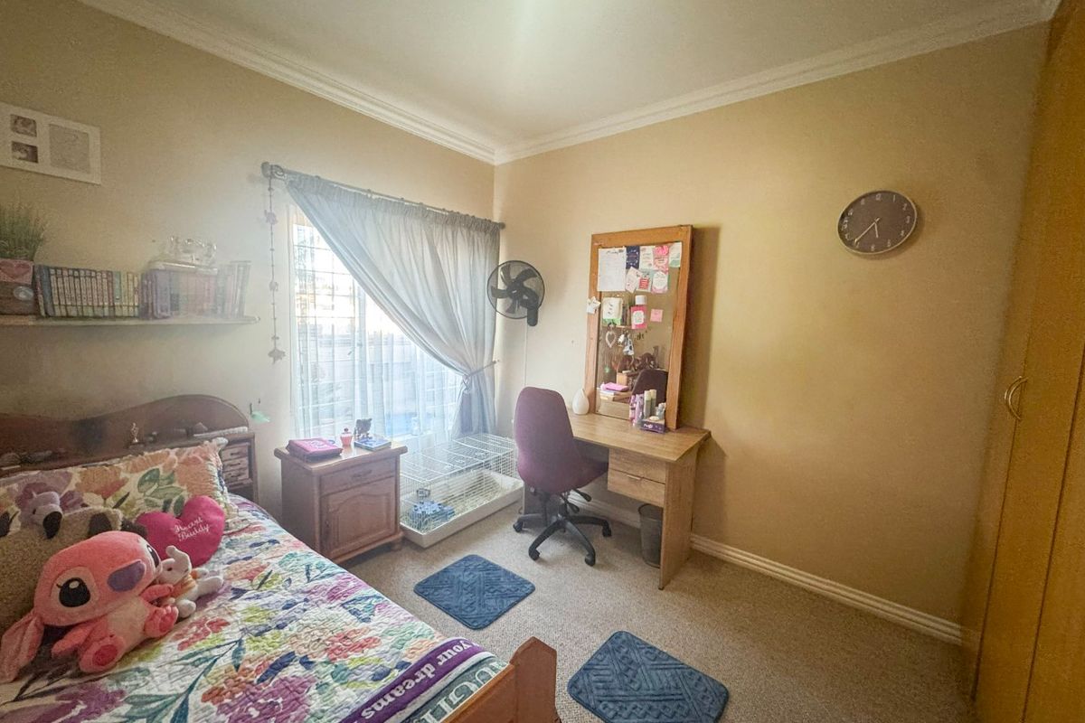 A standard bedroom featuring carpeted flooring, built-in cupboard space, and a window with curtain tracks.