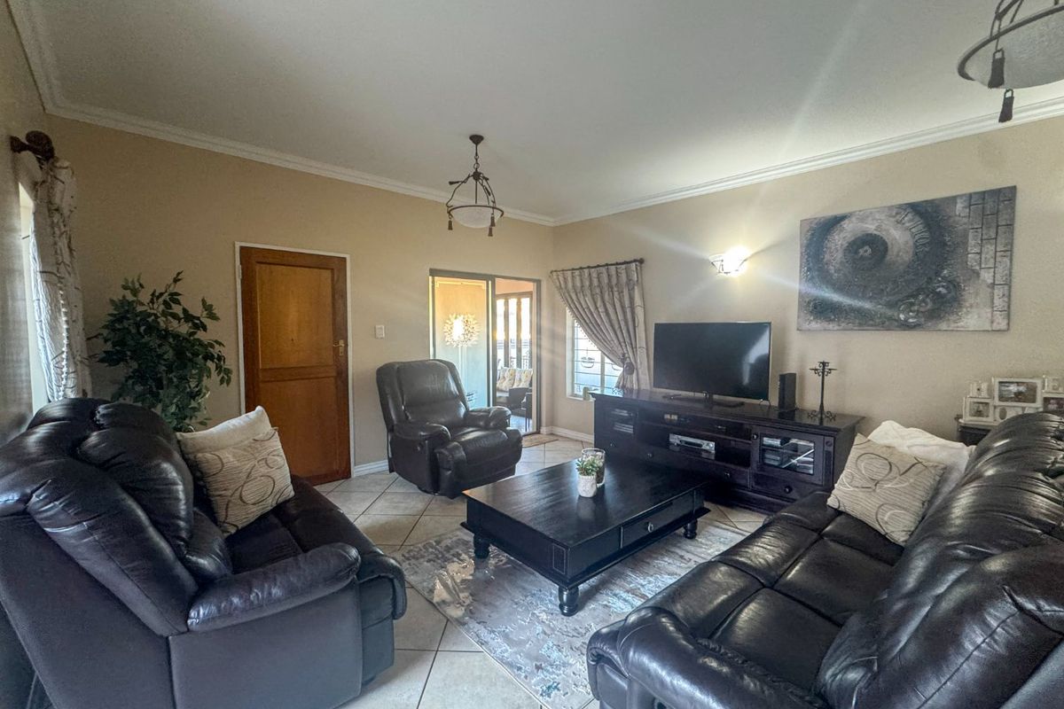 A comfortable living room featuring tiled flooring, crown molding, and sliding glass doors that provide access to an outdoor patio area.