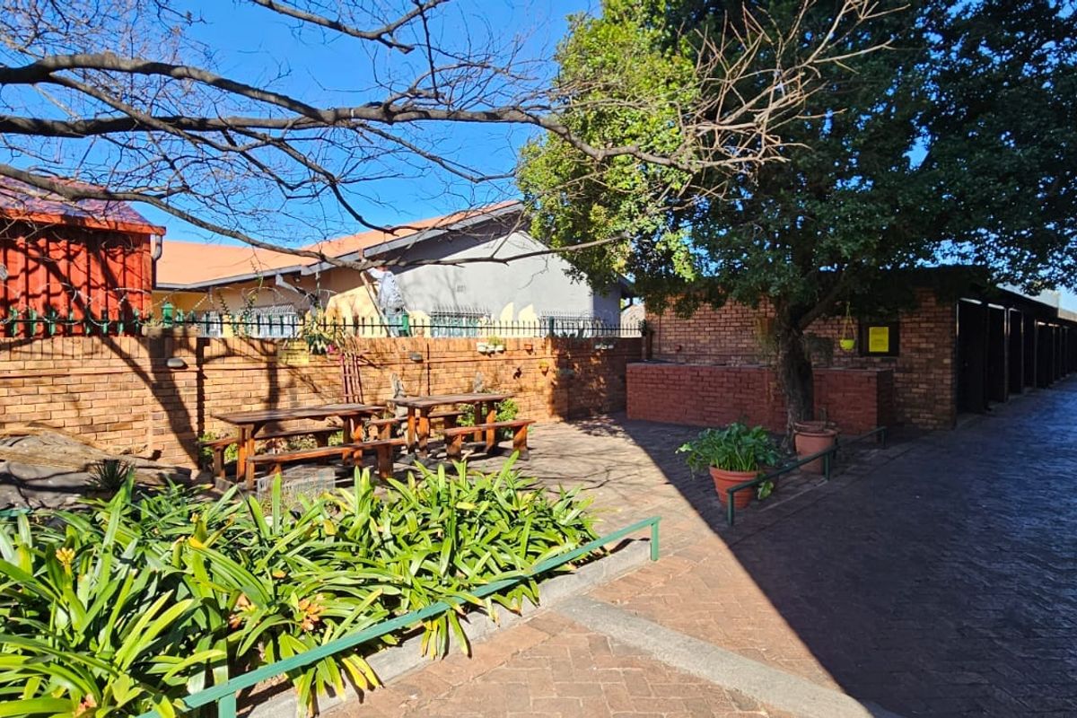 A communal outdoor courtyard area featuring brick boundary walls, paved flooring, and established trees within an apartment complex setting.