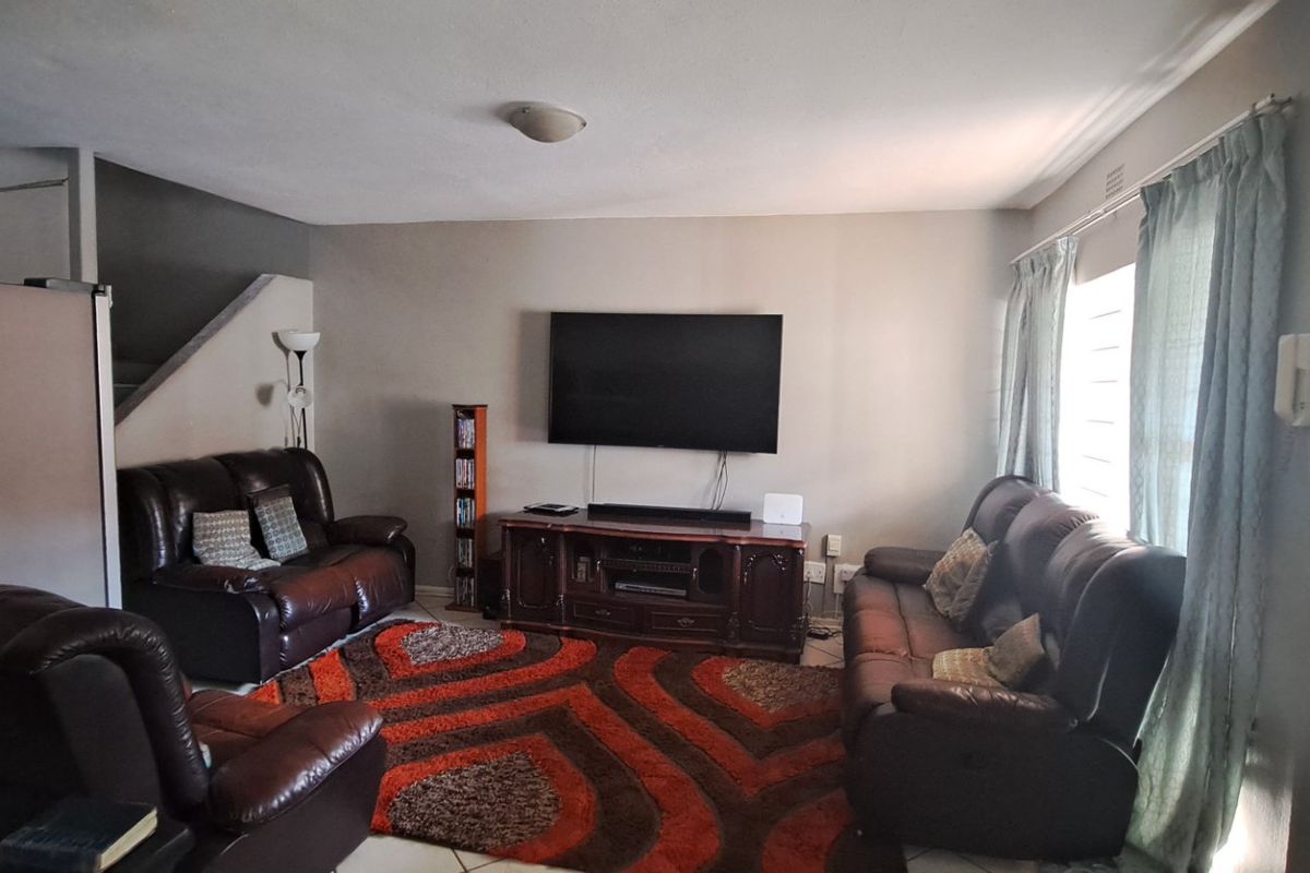 A spacious living room featuring tiled flooring and neutral wall tones, providing a functional and comfortable area for relaxation.