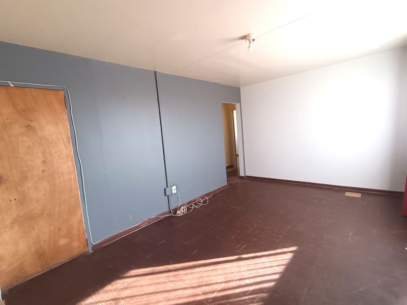 An empty living room featuring dark vinyl flooring, two-tone painted walls, and exposed surface-mounted electrical conduit.