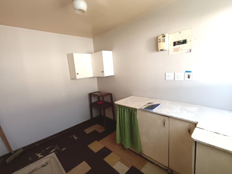 A functional utility space featuring built-in cabinetry, an electrical distribution board, and vinyl flooring, offering potential for renovation or improved storage organization.