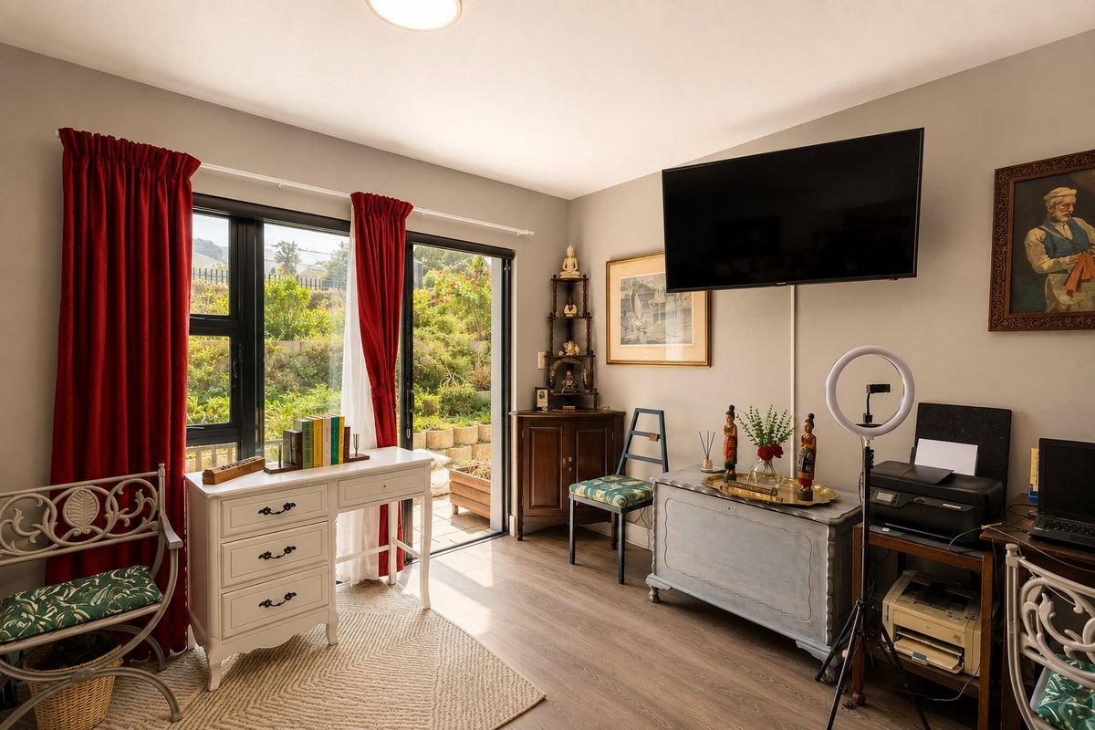 A bright living area featuring laminate flooring, a wall-mounted television, and large sliding glass doors providing direct access to the garden.