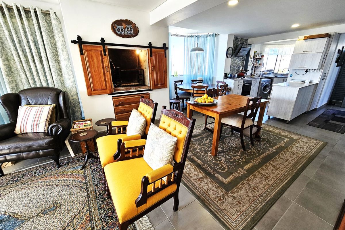 Spacious open-plan living and dining area featuring a built-in indoor braai, tiled floors, and a functional kitchen with integrated appliances.