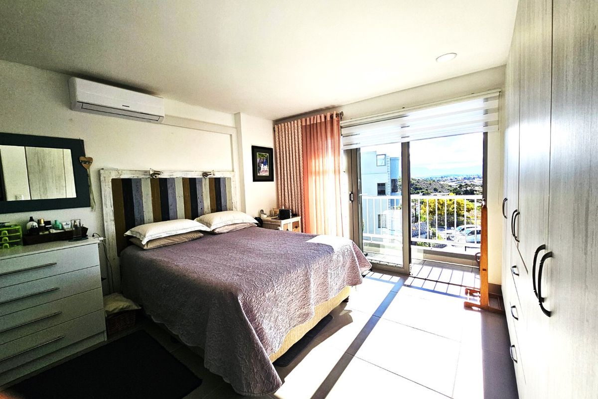 Bright bedroom featuring built-in cupboards, tiled flooring, and a sliding glass door providing direct access to a balcony with scenic views.