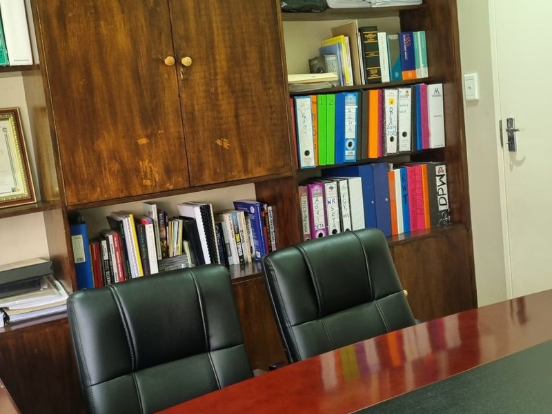 A home office featuring built-in wooden cabinetry and shelving units, providing ample storage space for documents and files.