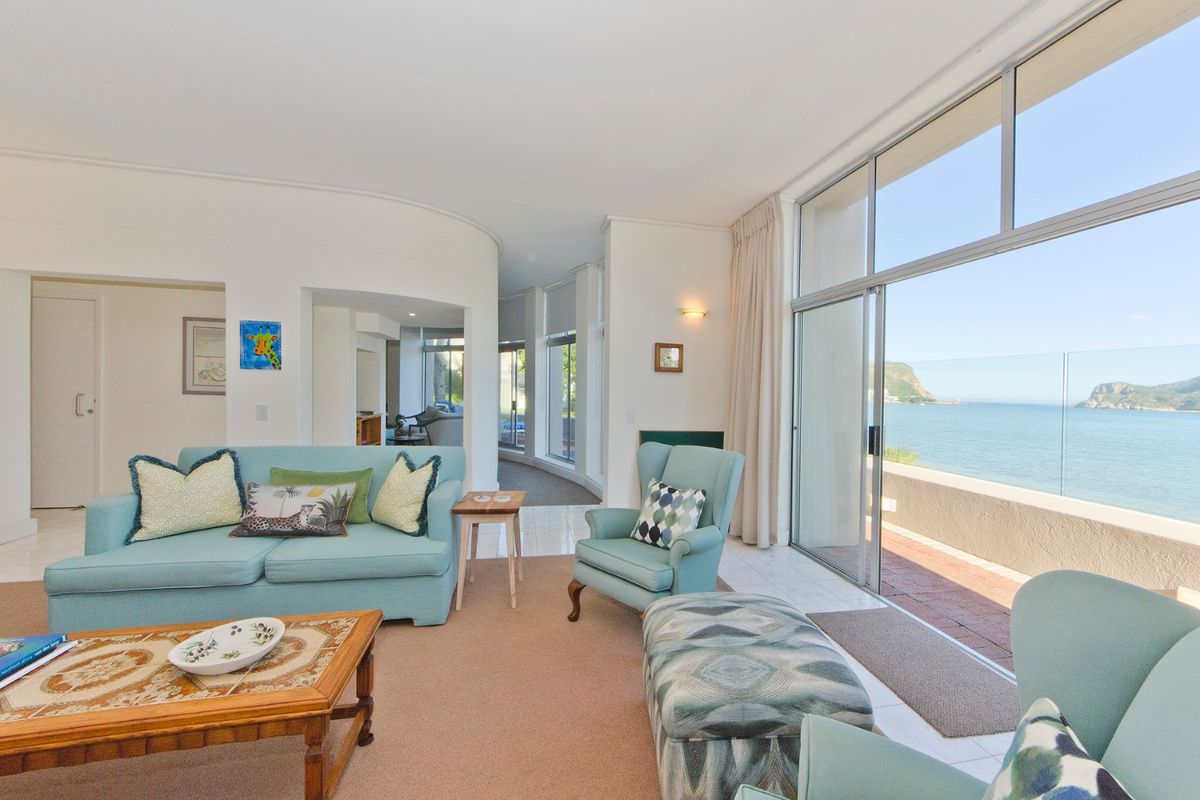 Spacious living room featuring large sliding glass doors that open to a balcony with stunning ocean views and a unique curved wall design.