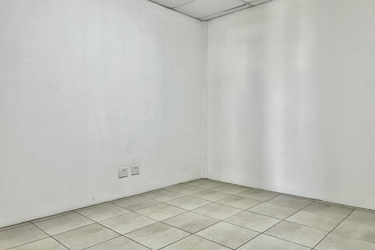 A vacant, neutral office space featuring tiled flooring, a suspended ceiling, and integrated electrical power outlets, ready for custom fit-out.