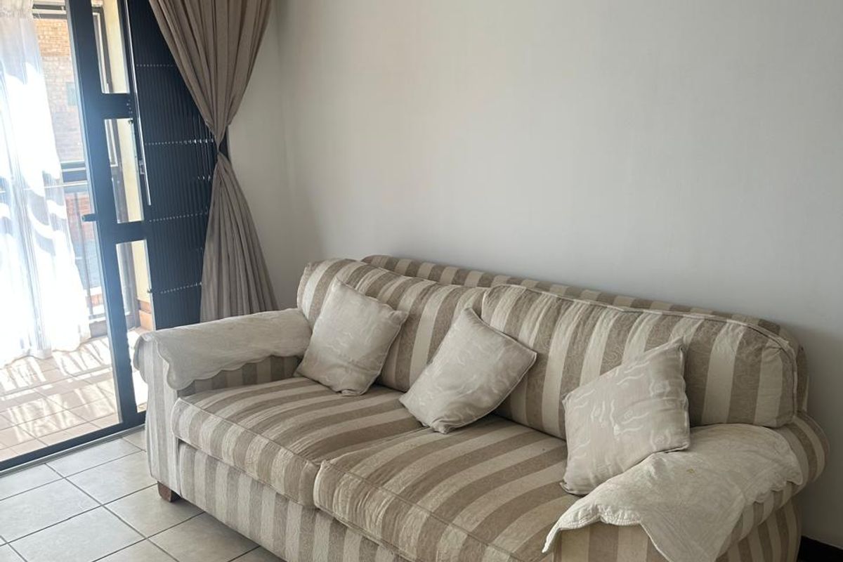 A living room area featuring neutral tiled flooring and a sliding glass door providing access to an outdoor space.