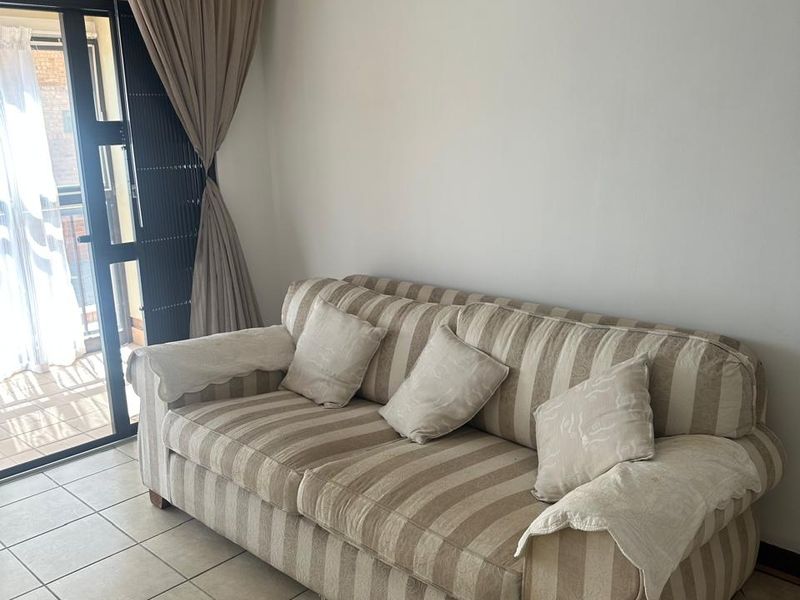 A living room area featuring neutral tiled flooring and a sliding glass door providing access to an outdoor space.