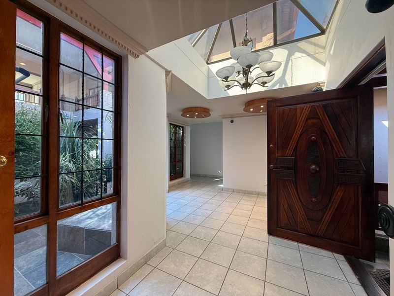 Spacious entrance hall featuring tiled flooring, a large skylight providing natural light, and a solid timber front door.