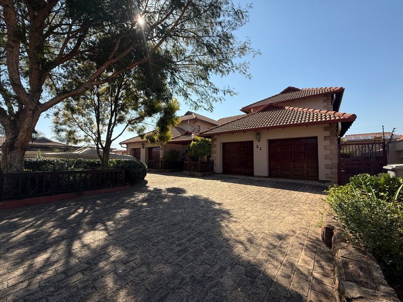 Front view of a well-maintained house featuring a double garage, paved driveway, and attractive stone cladding details.