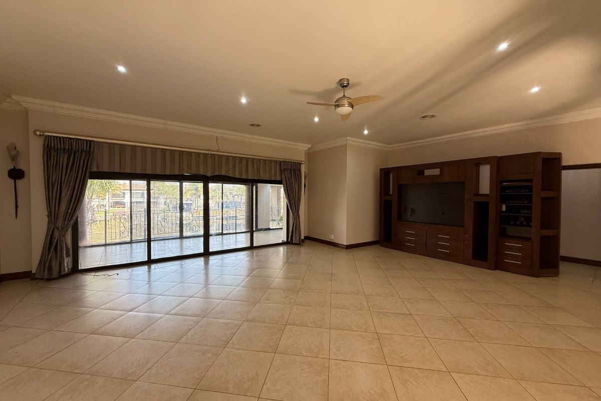 Spacious living room featuring large sliding glass doors leading to a patio, tiled flooring, recessed lighting, and a built-in wooden entertainment unit.