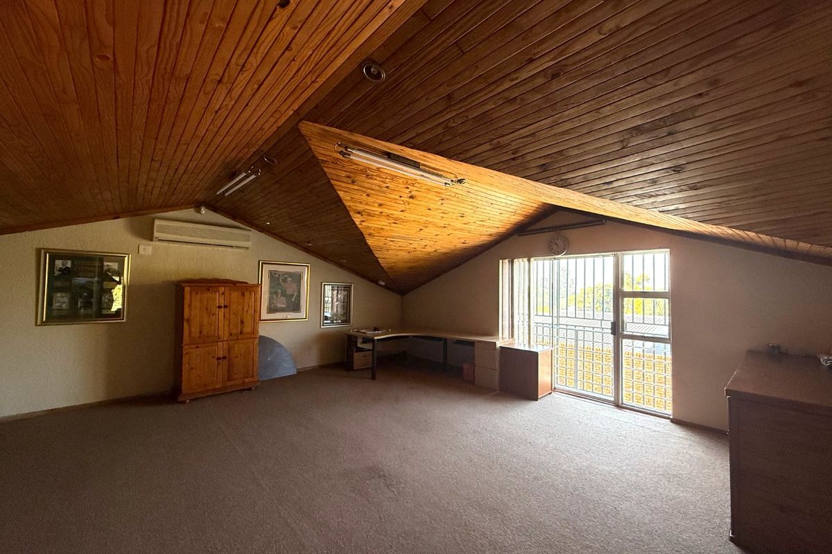 Spacious bedroom featuring a vaulted timber-clad ceiling, built-in desk, split-system air conditioning, and access to a balcony through a secure door.