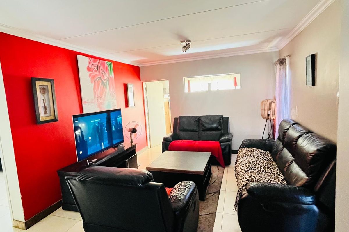 A living room featuring tiled flooring, cove cornicing, and a bold red accent wall, providing a functional space for relaxation.