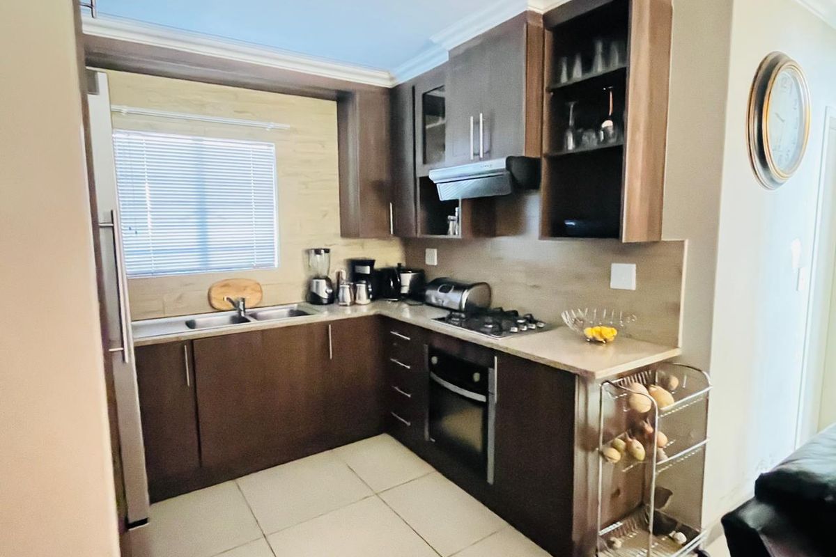 A functional kitchen featuring dark wood cabinetry, laminate countertops, a gas hob, built-in oven, and tiled flooring.