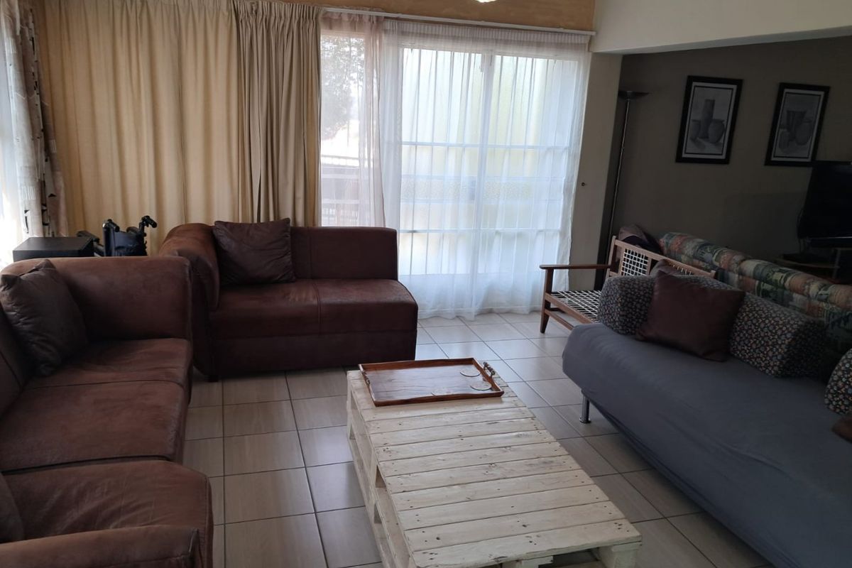 A living room featuring tiled flooring and a large sliding glass door providing access to the exterior.