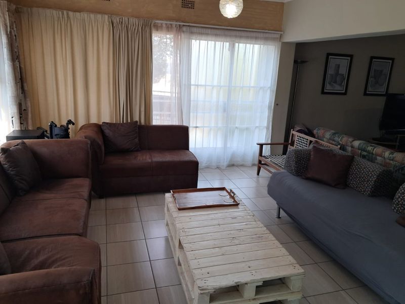 A living room featuring tiled flooring and a large sliding glass door providing access to the exterior.