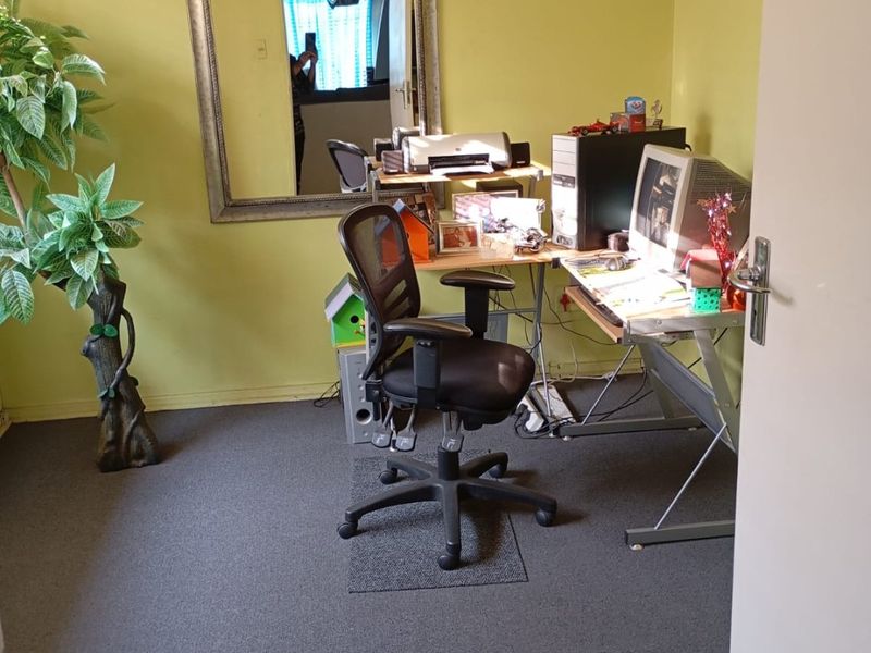 A functional home office space featuring carpeted flooring and neutral wall finishes, suitable for a dedicated workspace or study area.