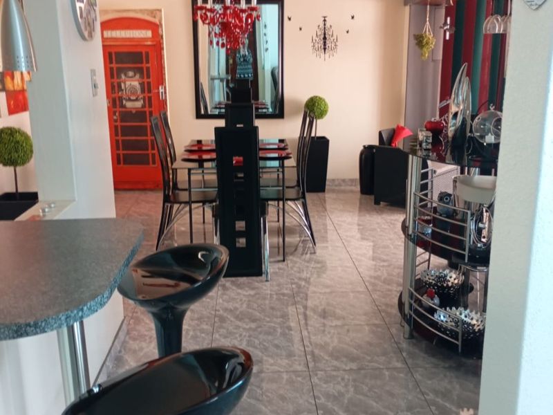Open plan living and dining area featuring tiled flooring, a breakfast bar, and coved ceilings, providing a functional space for daily living and entertaining.