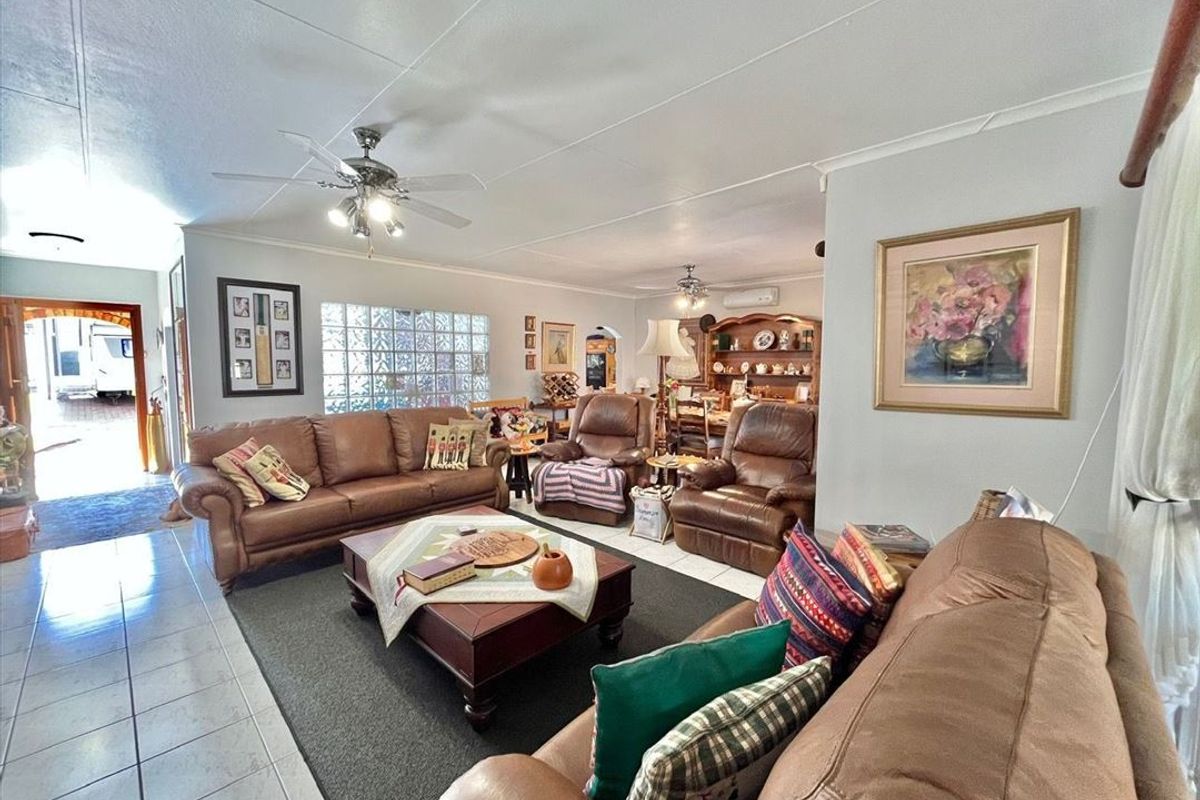 Spacious open-plan living and dining area featuring tiled flooring, ceiling fans, and a distinctive glass block window providing natural light.