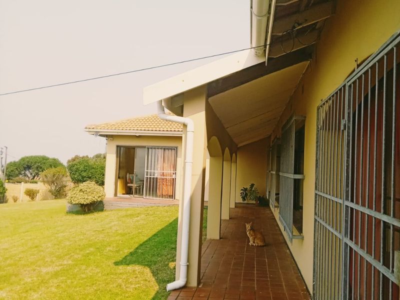 A covered patio walkway featuring tiled flooring, security gates, and access to the garden and main house interior.