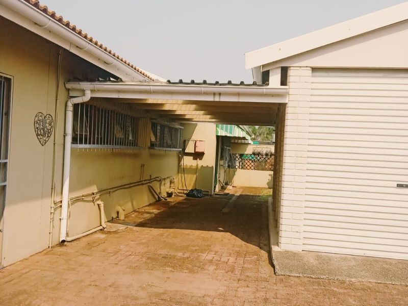 A covered carport area connecting the main house to the garage, featuring brick paving and functional guttering systems.