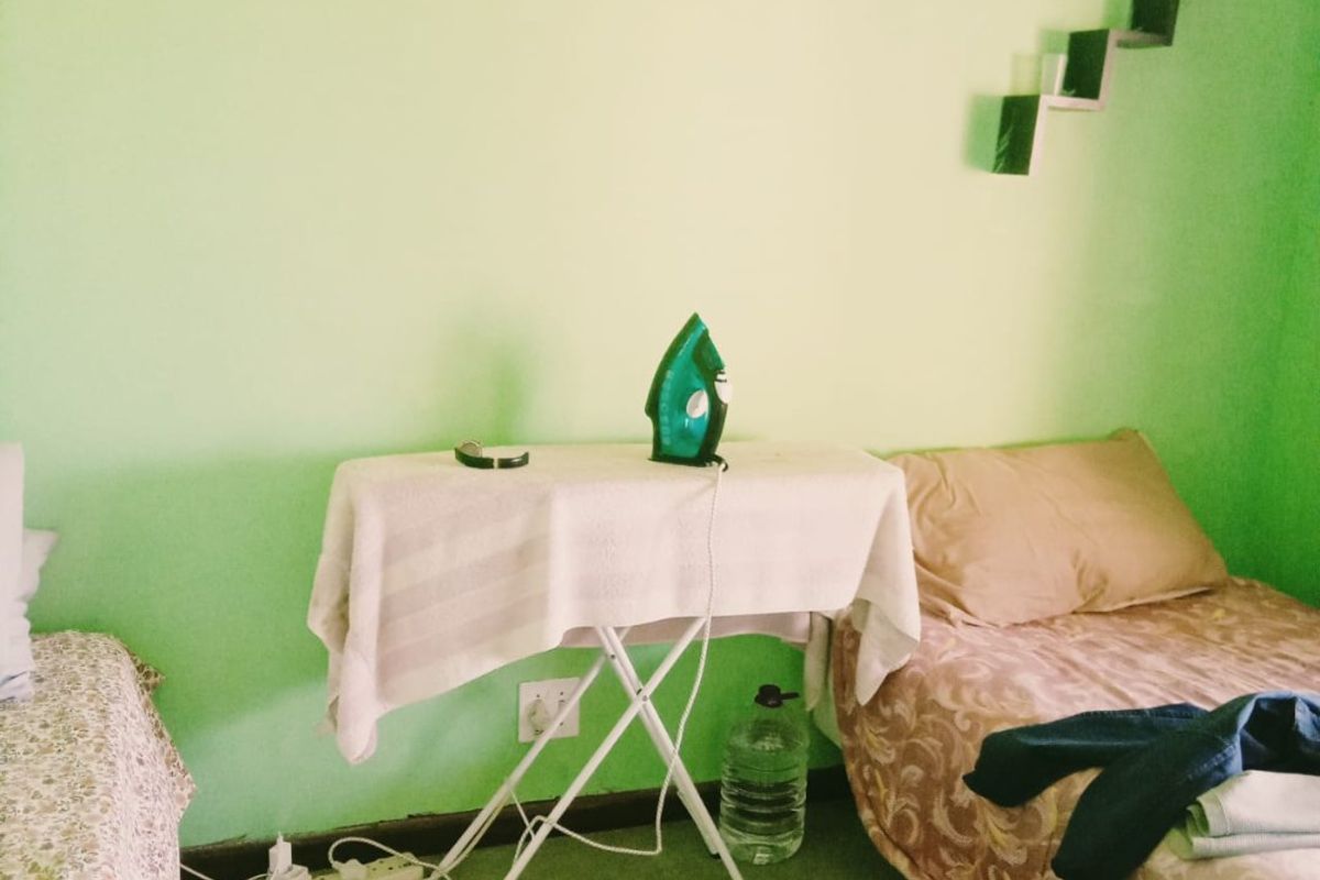 A bedroom featuring green walls and wall-mounted decorative shelving units.