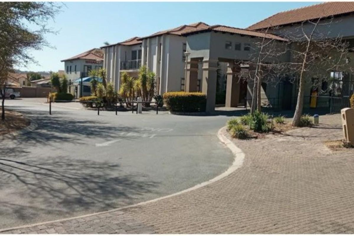 Front view of a commercial property complex featuring a paved driveway, covered entrance portico, and established garden landscaping.