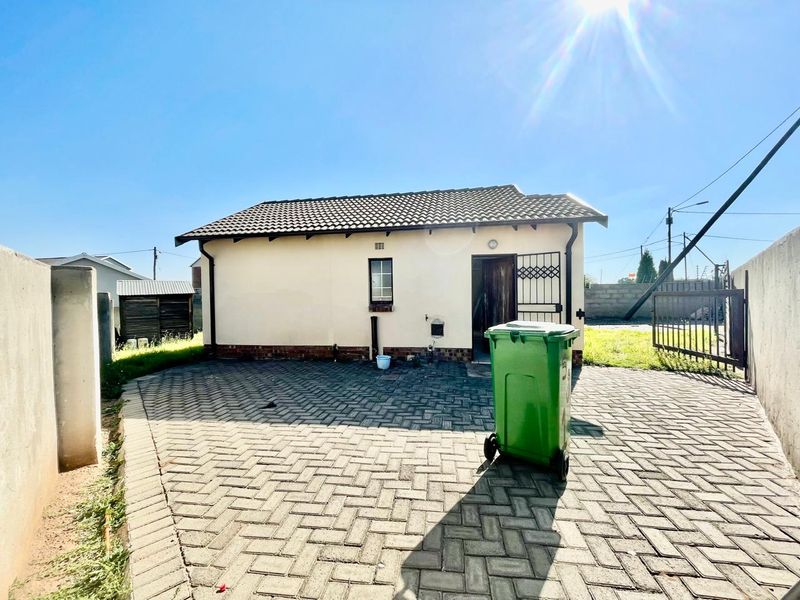 Rear view of the property featuring a paved courtyard, tiled roof, and secure gated access.