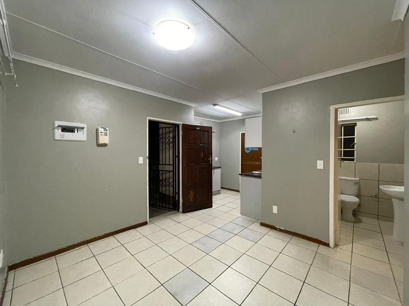 An open-plan living area featuring tiled flooring, an integrated kitchen space, and direct access to an adjacent bathroom.