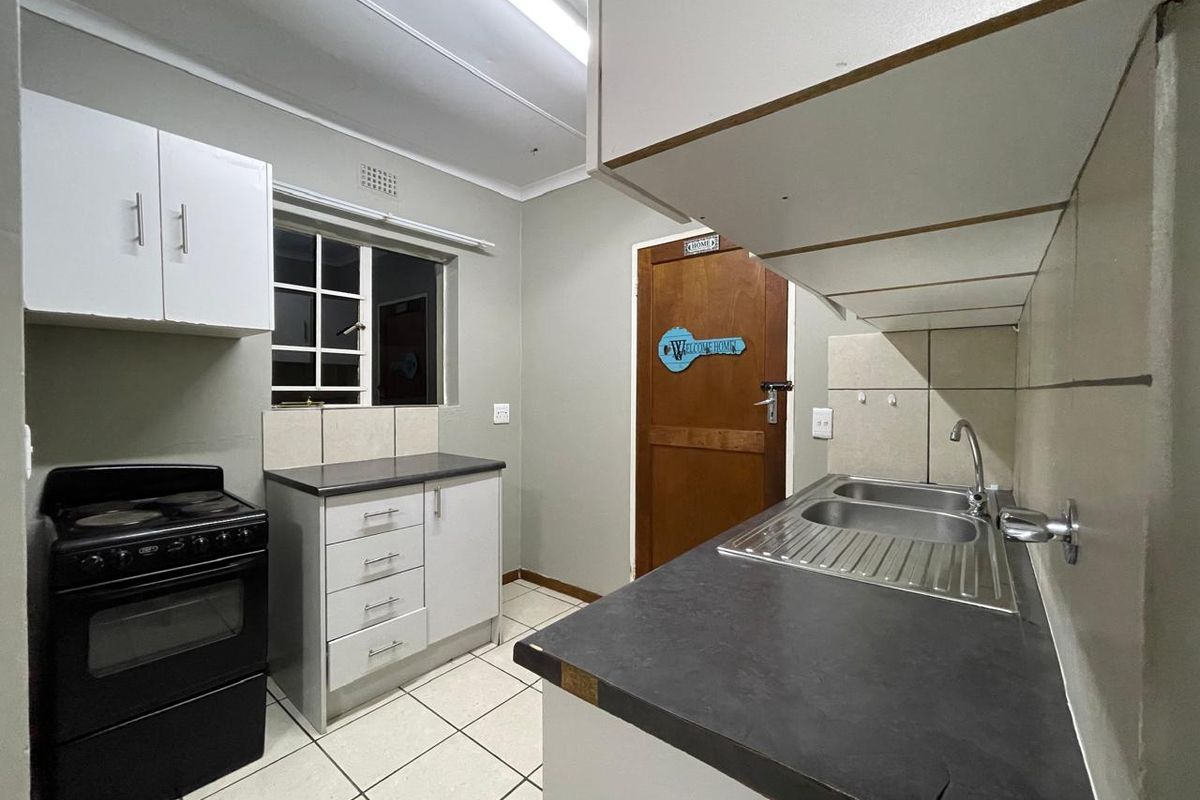 A functional kitchen featuring built-in cabinetry, laminate countertops, a stainless steel double sink, and tiled flooring.