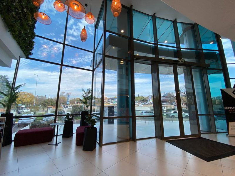 Modern commercial entrance lobby featuring floor-to-ceiling glass curtain walls, tiled flooring, and a vertical garden, providing a bright and professional reception area.