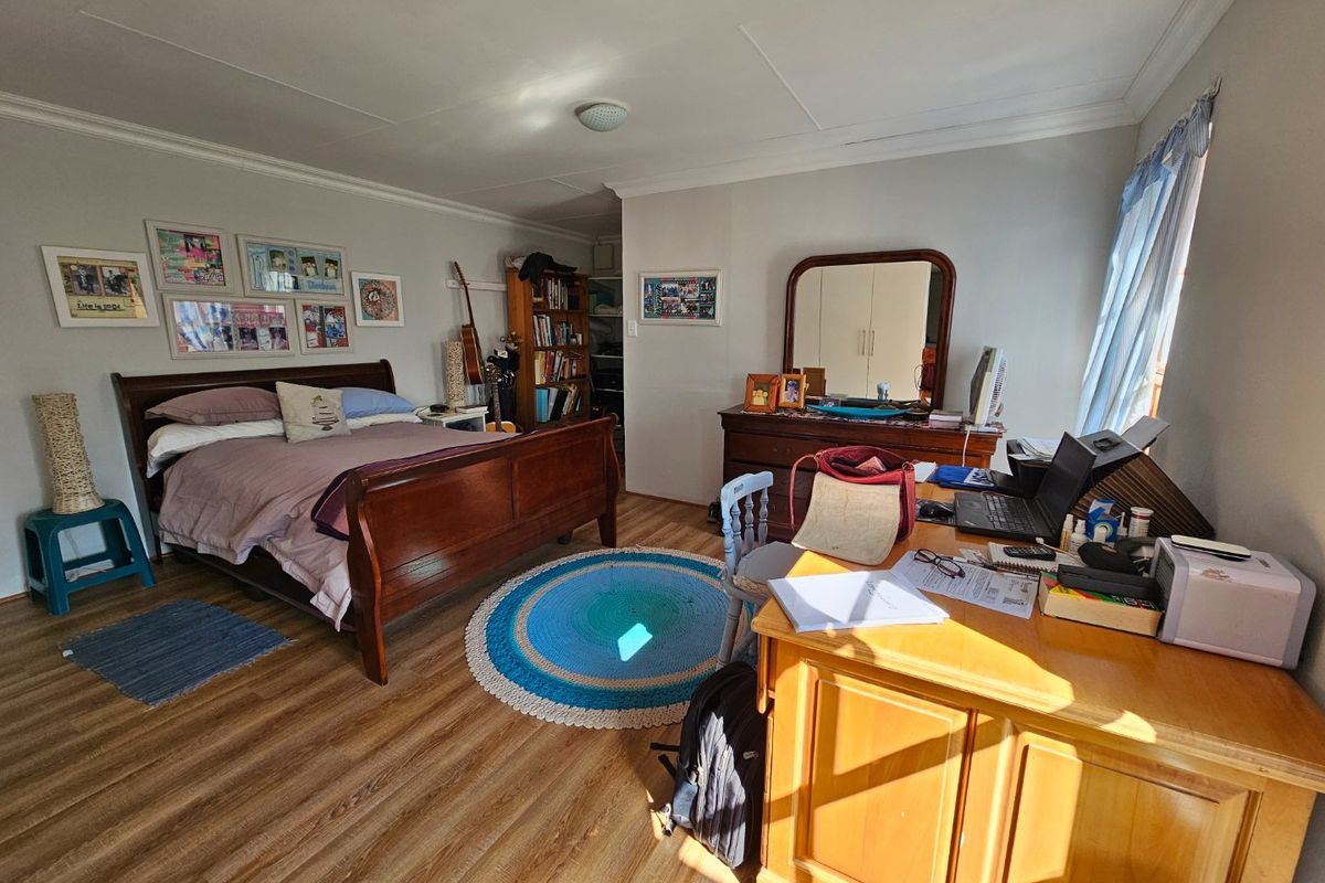 A spacious bedroom featuring laminate flooring and neutral wall finishes, offering a functional layout suitable for various furniture arrangements.