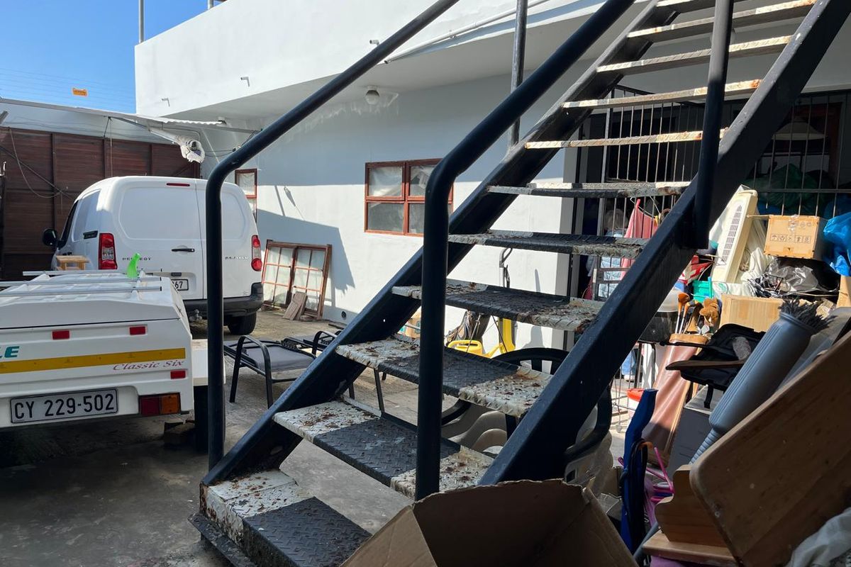 Rear exterior area featuring a metal staircase with visible signs of corrosion and wear, providing access to the upper level of the commercial property.