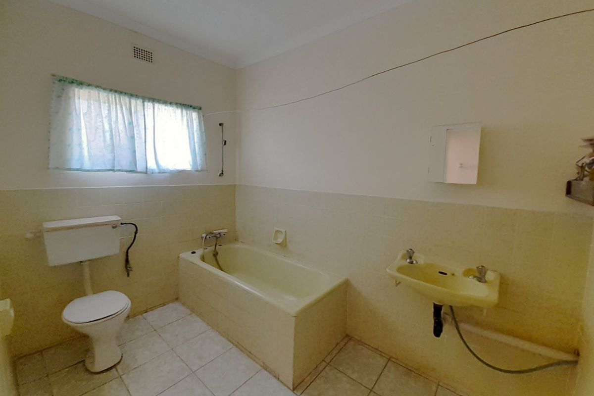 A dated bathroom featuring a bathtub, wall-mounted basin, and toilet with original tiling, offering significant potential for a modern renovation.