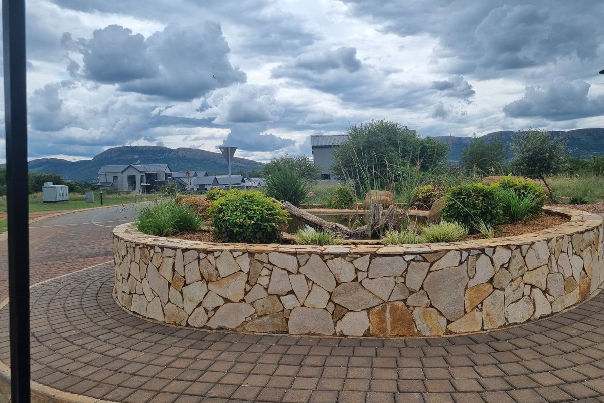 A well-maintained circular stone garden bed with integrated landscaping and a paved walkway in a residential estate setting.