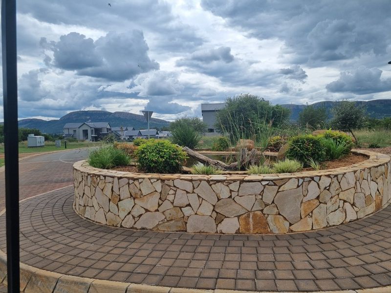 A well-maintained circular stone garden bed with integrated landscaping and a paved walkway in a residential estate setting.