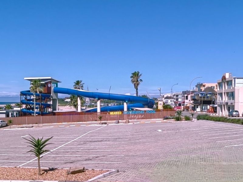 Commercial property exterior featuring a large paved parking area and a prominent water slide facility adjacent to the swimming pool area.