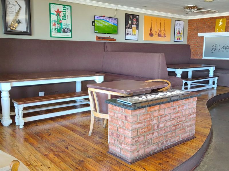 A commercial lounge area featuring raised timber flooring, a central brick fireplace, and integrated booth seating against a feature brick wall.